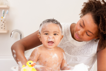 a lady sat next to her baby in a bubble bath