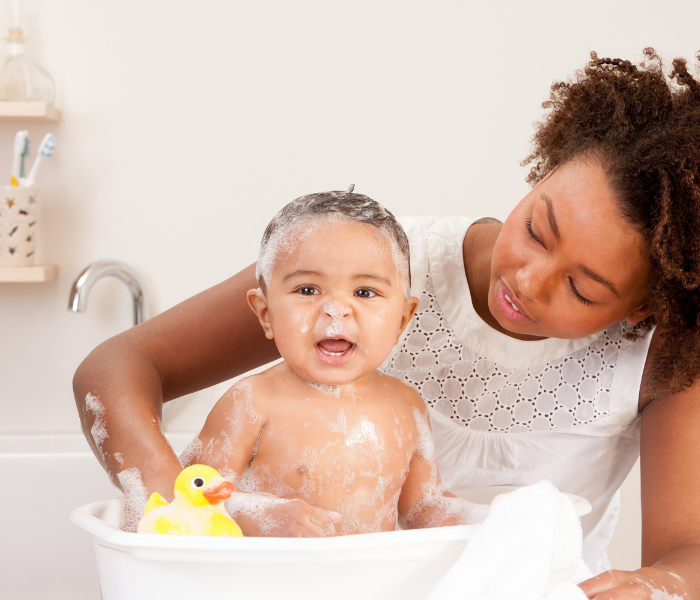 a lady sat next to her baby in a bubble bath