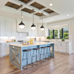 open plan kitchen with white cupboards and a kitchen island with stools