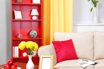 living room showing red bookcase, cream sofa with red cushion.Yellow flowers in a vase on wooden coffee table and yellow curtains