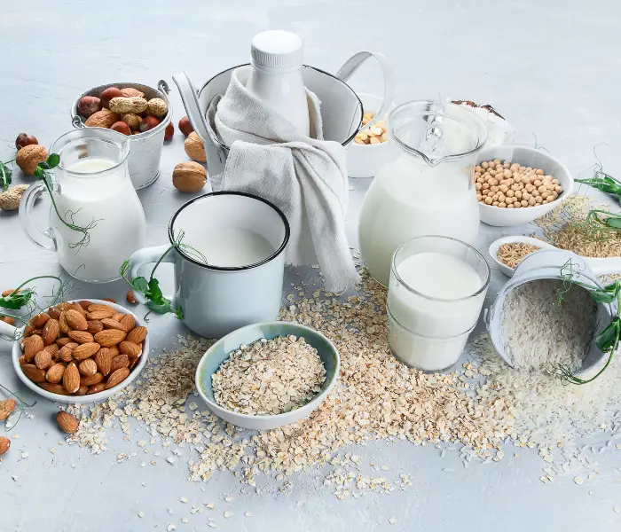 various jugs of milk with nuts and oats in bowls around