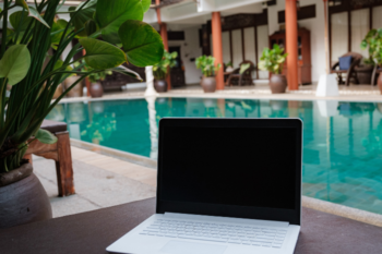 laptop on a table with a pool in the background