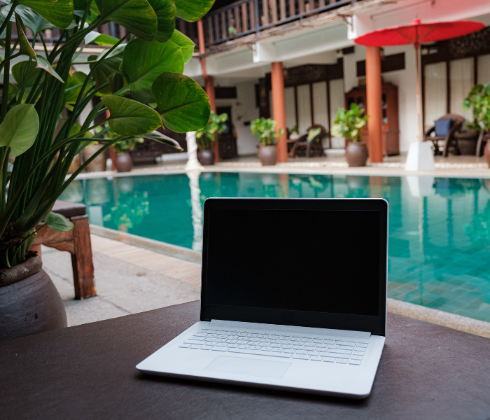 laptop on a table with a pool in the background