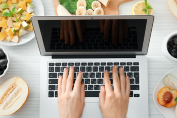 laptop with plates of fruit around it