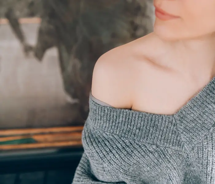 a lady wearing a grey off the shoulder jumper
