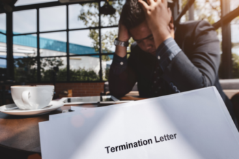 man sat down with his head in his hands and a termination letter showing