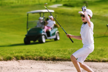 kid in whitw clods with glases holding golf club and couple in golf cart