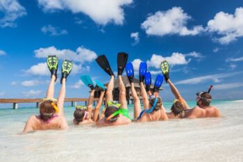family led on their backs in the sea with their legs up in the air wearing flippers