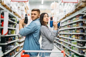 man and lady in diy store shopping aisle holding a drill each
