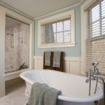 bathroom showing a bath and shower. there are two windows with white blinds