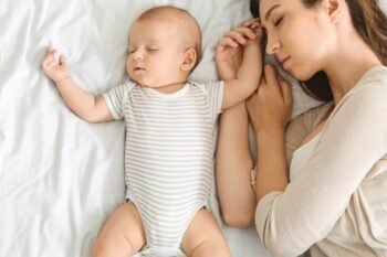 a lady and baby asleep in bed