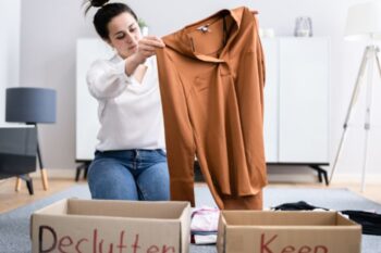 a lady holding up a brown shirt abover two boxes, one says declutter, the other says keep