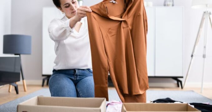 a lady holding up a brown shirt abover two boxes, one says declutter, the other says keep
