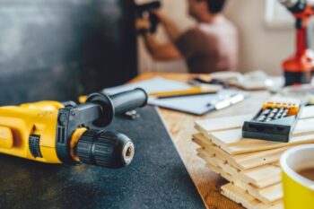 electric drill in the forefront of the pictyre with a man working in the background