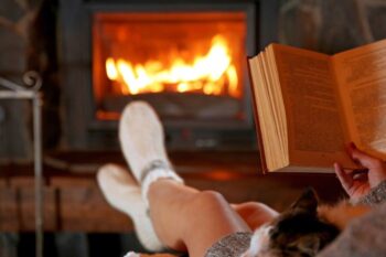 lady reading book with fire roaring in the background