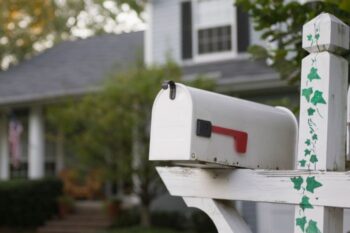mailbox on white post with green leaves painted