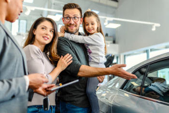 family stood next to a car i a car sales room