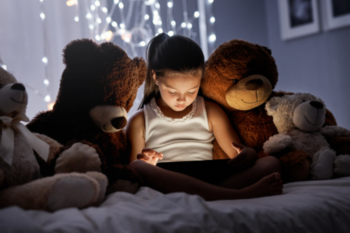 a girl reading next to teddies with lights in the back