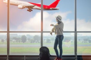 lady stood at a window airport window with plane taking off in background. canva pro license