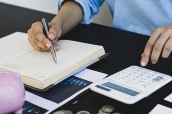 someone doing accounts with coins, pad of paper and calculator
