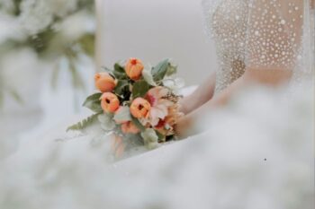 bride wearing white bridal dress holding orange flower bouquet