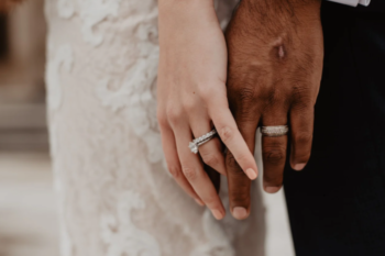 man and womens hands touching with wedding rings in focus