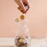 hand putting coins into a jar