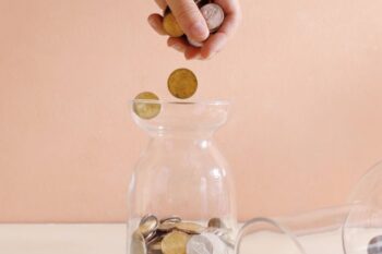 hand putting coins into a jar