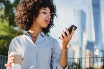 lady looking at phone and holding take away coffee