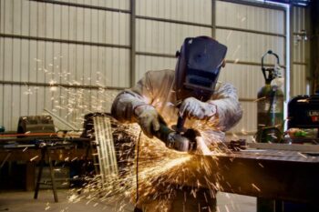 A man in a welding mask is grinding metal