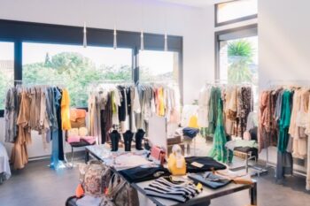 Closet with hanging clothes and folding table showcasing curated fashion collection, bright natural lighting, modern interior design.