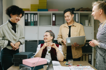 Group of diverse colleagues enjoying a casual chat and brainstorming session in a modern office environment, promoting teamwork and creativity.