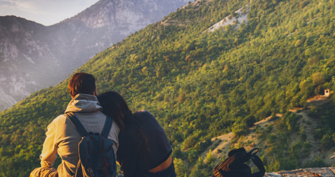 couple sat on a wall with mountains in front of them