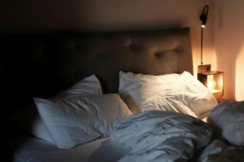 unmade bed with light at side