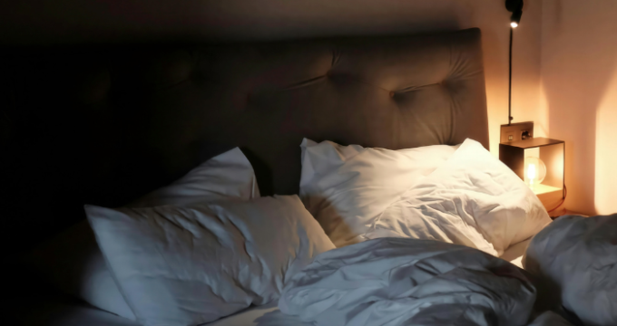 unmade bed with light at side