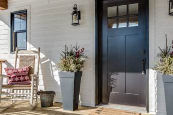 front porch with black door and rockinh chair to the side, nice planters